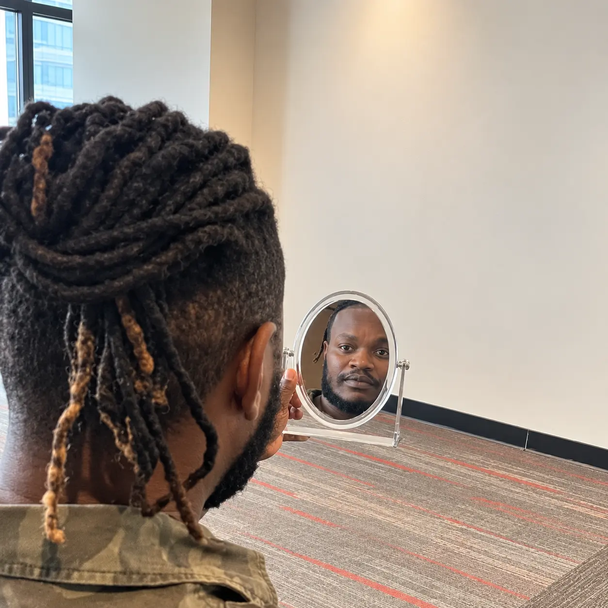 African man reviewing his braided hairstyle during a hair consultation in Nairobi